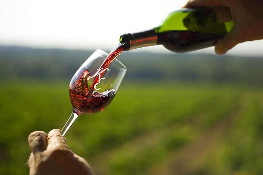 person pouring a glass of kiepersol wine in a field
